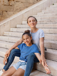 Mother and daughter sitting on stone stairs outdoor wearing t-shirts