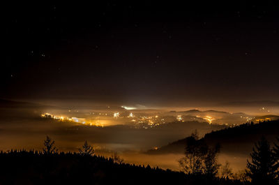 Silhouette trees on landscape against sky at night