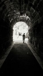 Rear view of man walking in tunnel