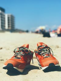 Close-up of shoes on sand at beach