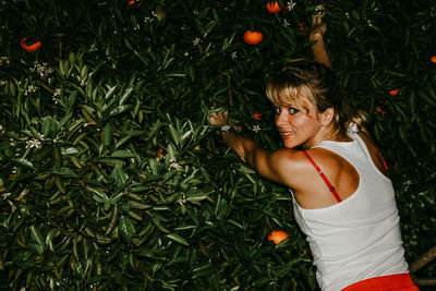 Woman standing by plants with oranges