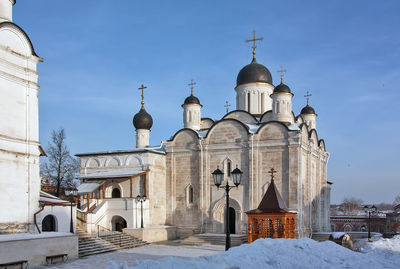 Church by building against sky during winter