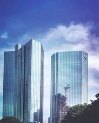 Low angle view of modern buildings against cloudy sky