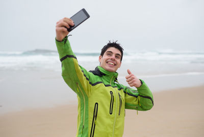 Man taking selfie at beach during rainy season