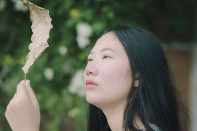 Close-up of young woman holding dry leaf