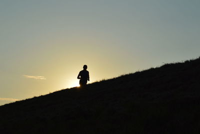 Silhouette person walking on landscape against sky