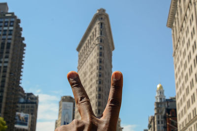 Flatiron building - low angle view of hand holding built structure against sky