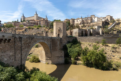 Arch bridge over river against buildings