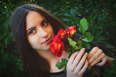 Thoughtful young woman holding red roses