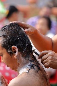 Cropped image of monk cutting hair of man during ordination