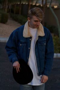 Fashionable young man wearing jacket standing on road