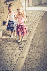 Siblings playing with bubbles while walking on sidewalk