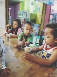 People looking at camera while sitting on table