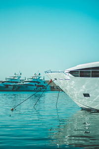 Fishing boats moored in sea against clear blue sky