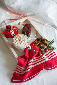 Christmas breakfast on a white wooden tray decorated with festive decor and garland. 
