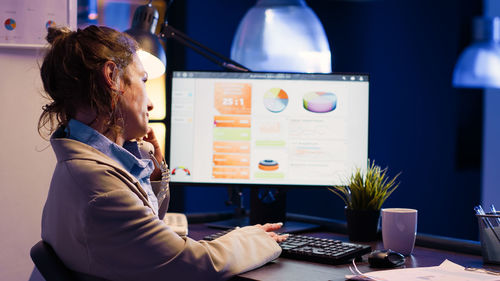 Side view of woman using laptop at office