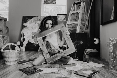 Black and white images of woman surrounded by art holding a frame