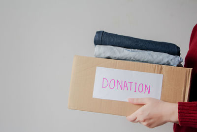 Cropped hand of woman holding gift box against white background