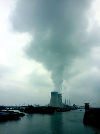 View of factory by sea against sky