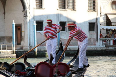 People standing by boats in canal