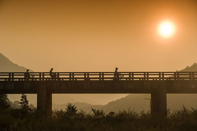 Silhouette man standing by sea against clear sky during sunset