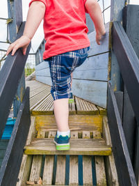 Low section of boy moving on wooden steps at park