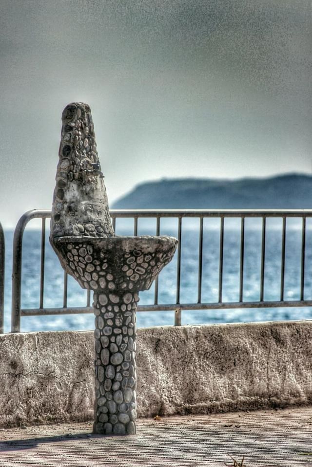 sky, tranquility, water, nature, mountain, focus on foreground, tranquil scene, day, wood - material, close-up, no people, outdoors, railing, metal, beauty in nature, clear sky, fence, scenics, sea, built structure