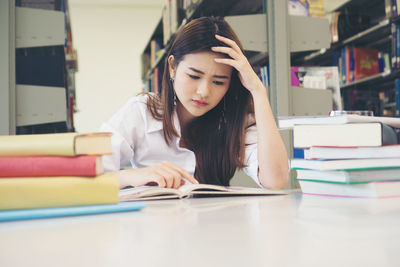 Tensed female student studying at table in library