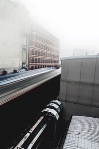 Blurred motion of vehicle by building in city against sky