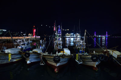 Boats moored in harbor at night