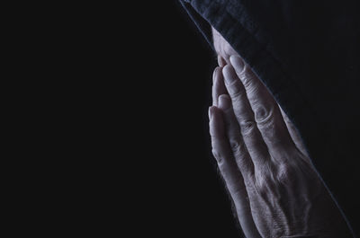 Close-up of man covering face against black background