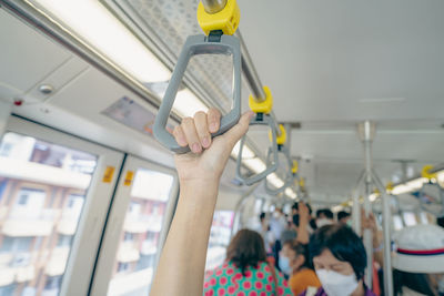 Woman hand firm grip safety handrail in elevated monorail train. mass transit system in modern city.