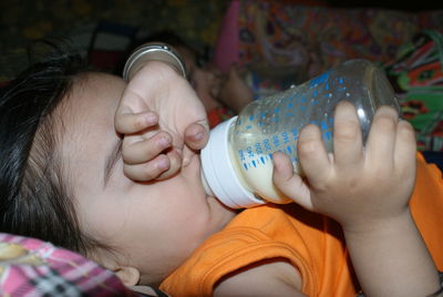 Close-up of baby boy drinking milk while lying on bed at home