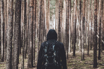 Man in hooded shirt standing against trees