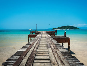 Scenic view of rustic wooden pier, turquoise water and white sand beach of koh mak island, thailand.