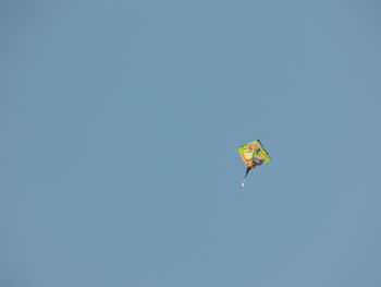 Low angle view of person paragliding against clear blue sky