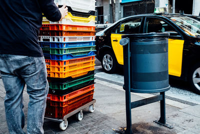 Low section of man pushing crates on footpath