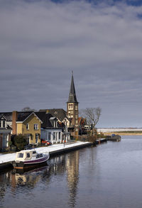 Boats moored in sea by buildings against sky