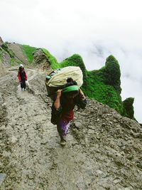 Rear view of people walking on rock formation against sky