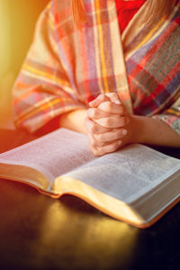 Midsection of woman reading book on table