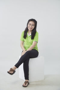 Portrait of smiling young woman sitting against white background