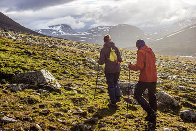 Rear view of men standing on mountain against sky