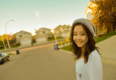 Portrait of smiling young woman standing against building