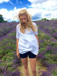 Young woman standing on lavender field against sky