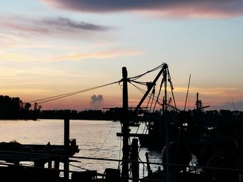 Silhouette bridge over river against sky during sunset