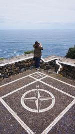 Rear view of man standing by sea against sky