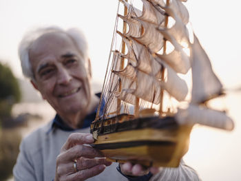 Man holding ship toy while standing outdoors