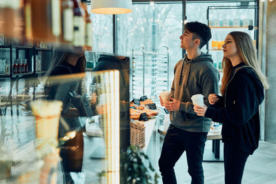 Friends doing shopping in a coffee shop.. people buying coffee and sweet snacks to go