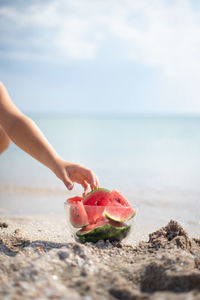 Low section of woman sitting on sand at beach