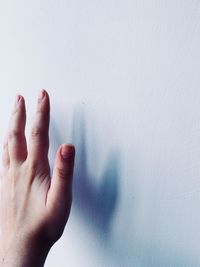 Close-up of person hand against white wall